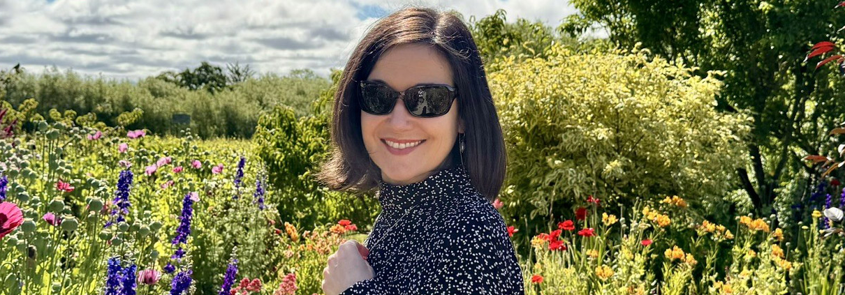 Becky Winkler standing among flower bushes. (PHOTO: Franklin College of Arts and Sciences)