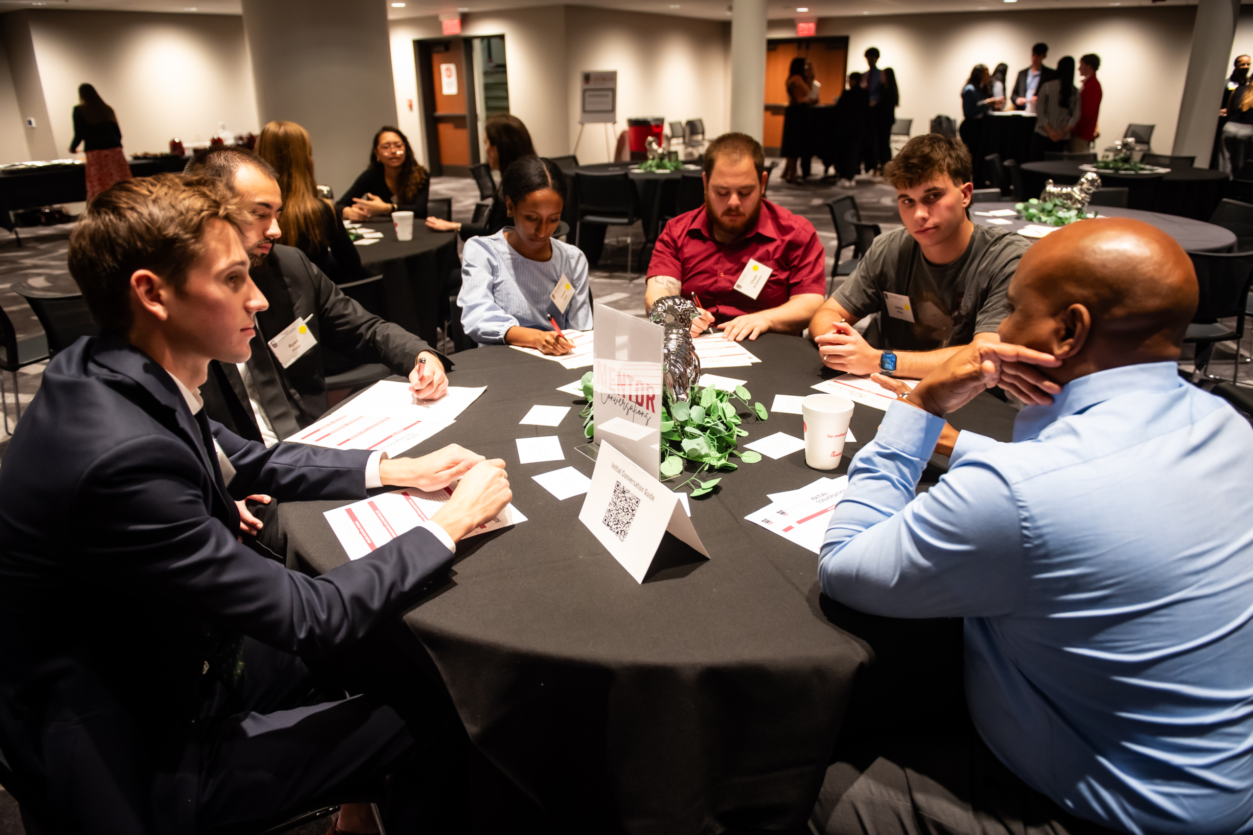 Mentors and mentees gather at a table. 