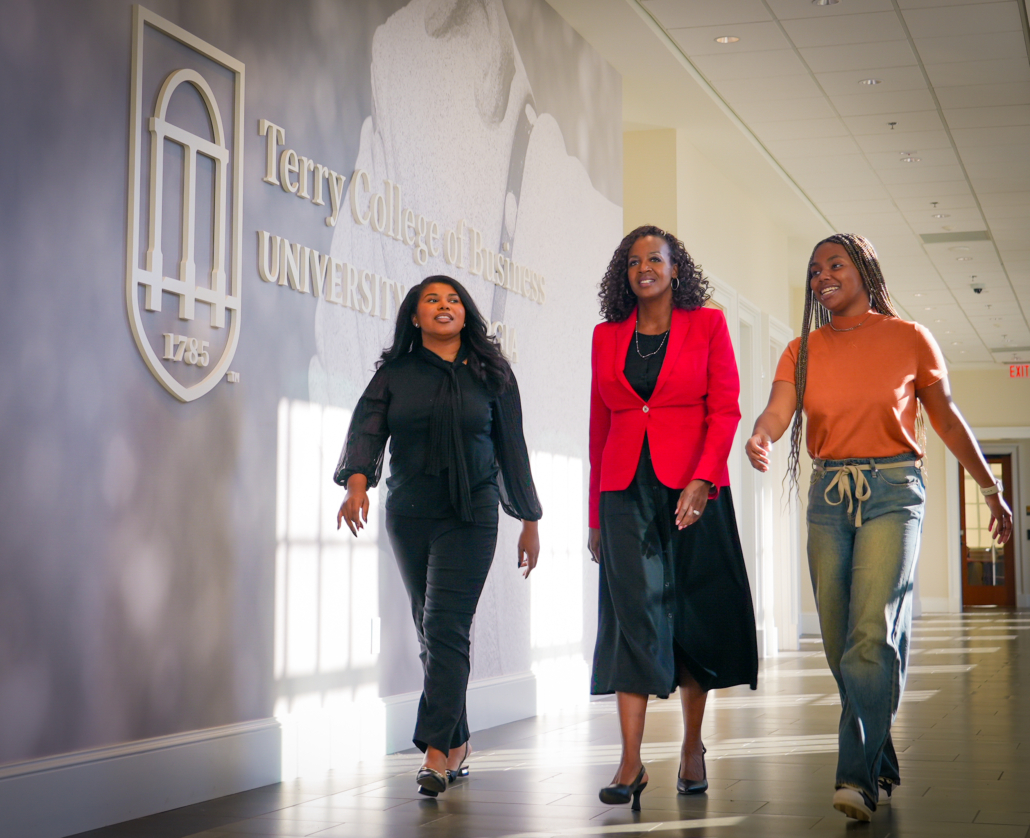 Rachel, Tia and Stevonna walk down a sunlit hall in the Terry College of Business.