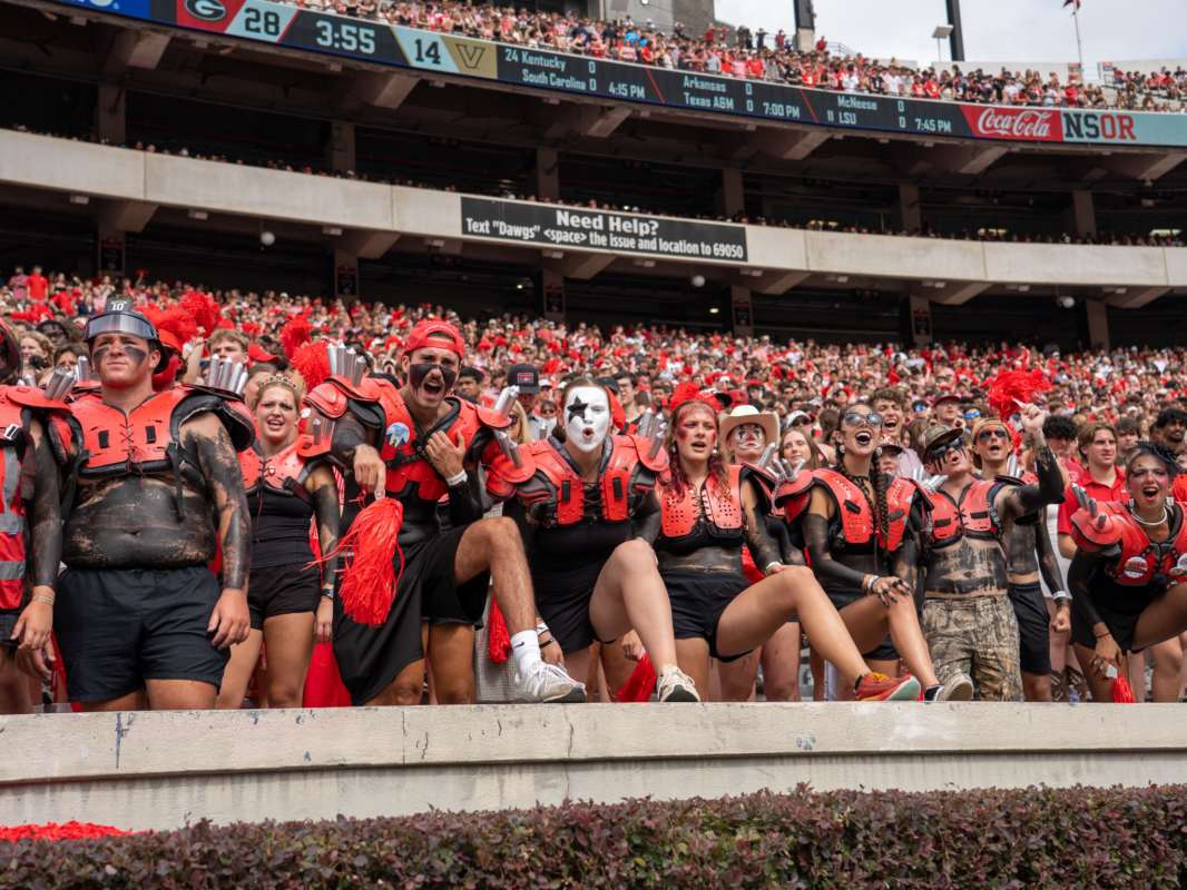 Several members of the Spike Squad make hype faces and have one leg on the ledge in front of them. They wear red football shoulder pads and have painted their bodies black.