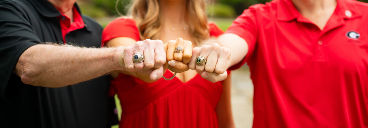 Three alumni display their class rings