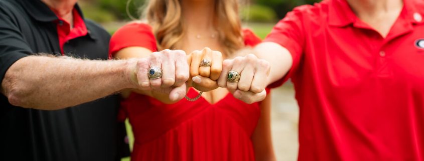 Three alumni display their class rings