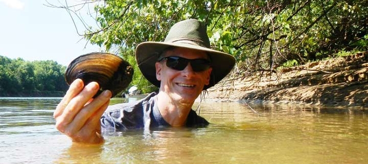 Frank Henning (PhD ’10) in holding up a river mussel.