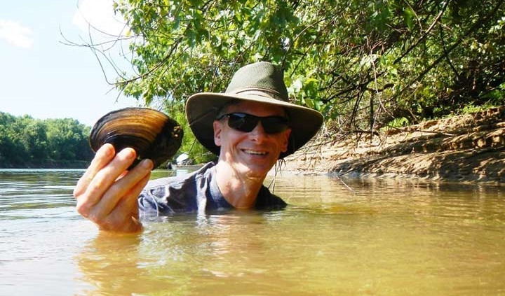 Frank Henning (PhD ’10) in holding up a river mussel.