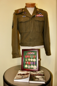 Harold Berkman's military uniform on display with various medals and two books placed on a table