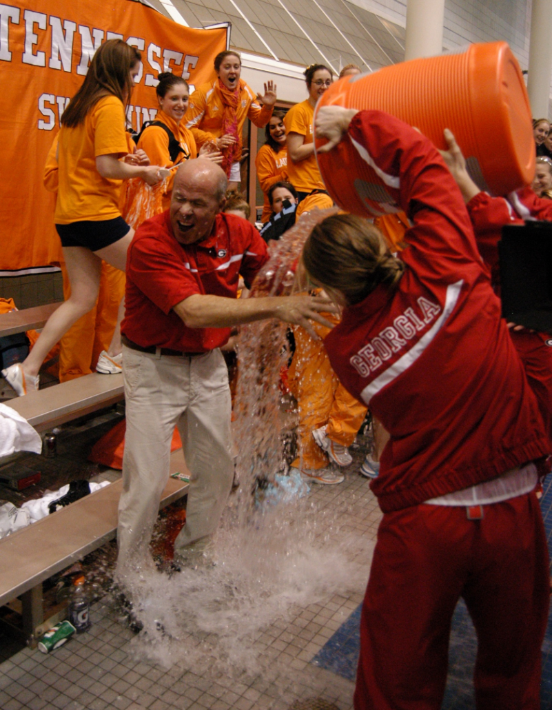 UGA swimmers celebrate by pouring water over Jack Bauerle.